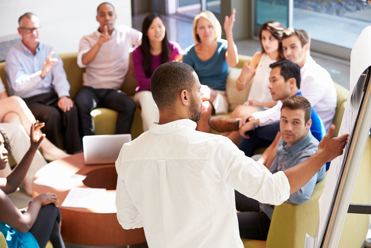 Man pointing to chart while teaching a group of people