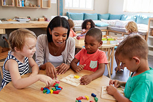 Teacher and young students playing with wooden blocks