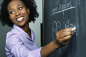 Teacher smiling and writing on blackboard