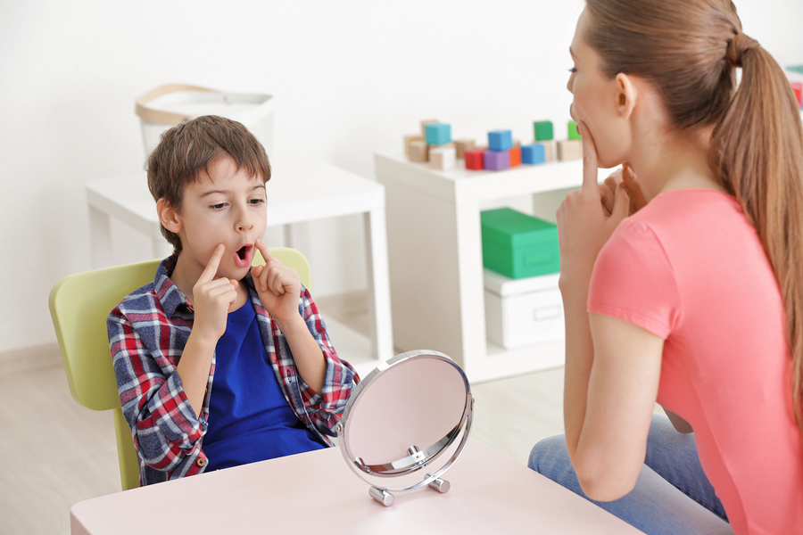 Speech Pathologist working with young boy to form sound correctly