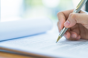 Hand holding pen and signing papers