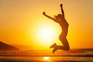 Silhouette of person jumping for joy against sunset background