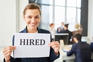 Young woman holding 'hired' sign