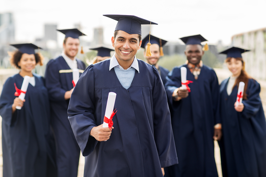 Students wearing graduation caps & gowns and holding diplomas