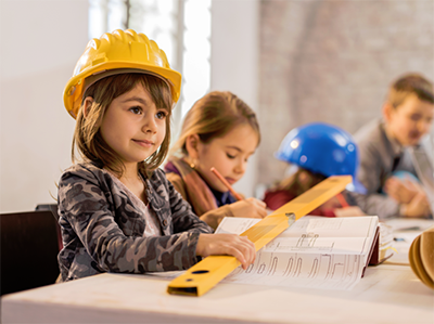 young girl in hard hard with classmates learning about construction