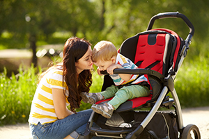 Mother sitting next to her baby in a stroller outside